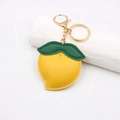 Détail d'un porte-clés citron en cuir avec feuille verte et fermoir doré brillant - Style Citron / Jaune