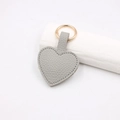 Detail of light gray lychee pattern leather heart keychain with golden metal clasp - Magnetic Heart / Gray