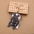 Handmade black and white leather pug keychain with golden metal clasp on paper background - White