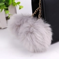 Dual grey faux rabbit fur pompoms with golden chain keychain on a black leather bag - 8cm / Gray