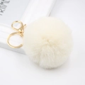 Detailed close-up of a fluffy cream faux rabbit fur pom pom keychain with gold hardware - Off-white