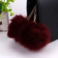 Close-up of deep red faux fur double pompom keychain with gold chain on bag - 8cm / Burgundy