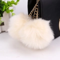Detail of soft cream-white faux fur poms with gold chain on a black leather bag - 8cm / Beige