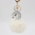 Close-up of fluffy white plush pom-pom with silver glitter unicorn head and golden clasp - Off White