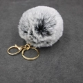 Macro-opname van pluizige zwart-witte faux fur pompon met een gouden karabijnhaak - Zwart-Wit Gemengde Stijl / donkergrijs