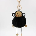 Close-up of fluffy black monkey plush keychain with golden metal clasp and faux fur ball - 8cm / Black