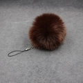 Detailed view of deep brown fluffy faux fur pompom with a black string and metal clasp - 8cm Faux Fur + Strap / Brown