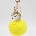 Close-up of fluffy yellow pompom unicorn keychain with gold sequins and metal clasp - Yellow
