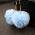 Detail of light blue faux rabbit fur double poms with gold chain on a black handbag - 8cm / Sky Blue