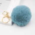 Detailed close-up of light blue fluffy faux fur ball keychain with gold lobster clasp - Teal