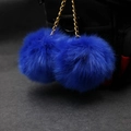 Detail of royal blue faux rabbit fur double pompom keychain with golden metal chain - 8cm / Dark Blue