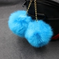 Detail of bright blue fluffy double pom-pom charms with gold chain on a black handbag - 8cm / Lake Blue