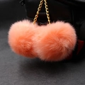Detail of soft coral orange double faux fur pompom charm on a black backpack - 8cm / Orange Red
