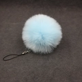 Detailed view of light blue faux fur pompom keychain with silver clasp and black cord - 8cm Faux Fur + Strap / Light Blue