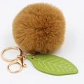 Detail of soft brown faux fur ball keychain with green leaf charm and gold metal clasp - Brown