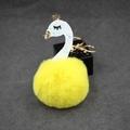Detailed close-up of a bright yellow faux fur pompom with a white swan and golden crown charm - Yellow