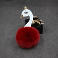 Close-up of a dark red fluffy pompom keychain featuring a glittery swan with golden crown - Burgundy