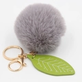 Detail of grey faux fur pompom keychain with green leaf charm and golden metal hardware - Gray