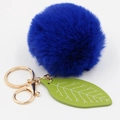 Detailed view of fluffy navy faux rabbit fur pom pom with green leaf charm on golden keychain - Sapphire Blue