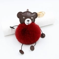 Detail of red faux fur pompom bear keychain with gold metal ring on white surface - Burgundy