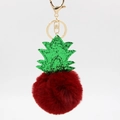 Close-up of a creative pineapple plush keychain with red fur pompom and green glitter leaves - Burgundy
