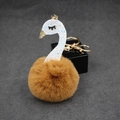 Close-up of fluffy brown pom-pom swan keychain with blue glitter neck and golden crown - Coffee