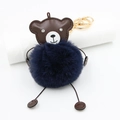 Close-up of cute brown bear plush keychain with navy faux fur ball and gold metal clasp - Navy Blue