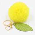 Detailed close-up of yellow faux rabbit fur pom pom with green leaf and golden keyring - Yellow