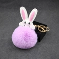 Detail of white rabbit keychain featuring soft purple faux fur pompom and golden metal hook - Taro Purple