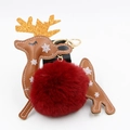 Close-up of brown leather reindeer keychain with red pompom and golden antlers - Burgundy