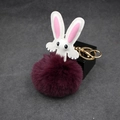 Detail view of the plush bunny keychain with purple faux fur ball and golden lobster clasp - Purplish Red