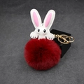 Macro detail of dark red faux fur pompom rabbit keychain with golden metal clasp - Burgundy