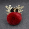 Close-up of fluffy red pompom keychain with golden reindeer antlers for Christmas bags - 8cm Pompom / Burgundy