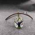 Vista macro de colgante ovalado de resina con árbol miniatura y alambre dorado - Estilo árbol blanco