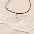 Vue rapprochée du collier artisanal avec fleur blanche séchée en pendentif résine - Blanc