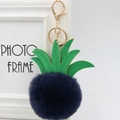 Close-up of blue pineapple faux fur keychain with green leather leaf and gold metal clip - 8cm / Navy Blue
