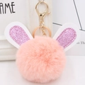 Close-up of pink fluffy pom-pom keychain with glittery purple rabbit ears and gold clasp - Gold Key Chain Style / Pink