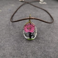 Detalle macro del colgante ovalado de resina con flores secas rosas y diseño de árbol - Estilo árbol - Magenta