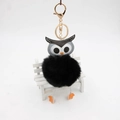 Détail d'un porte-clés hibou noir en peluche avec fermoir doré sur un mini banc blanc - 8cm / Noir