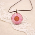 Macro d'un pendentif marguerite rose en fil de cuivre sur dentelle blanche - Série de Fleurs Pressées Réelles / Rose Bonbon