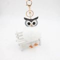 Détail du porte-clés hibou en fourrure blanche avec anneau doré sur banc blanc - 8cm / Blanc