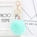 Close-up of fluffy mint green fur ball keychain with white rainbow unicorn pendant and gold clasp - Mint Green