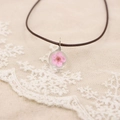 Gros plan sur pendentif en verre fait main avec fleur séchée rose et fil métallique - Rose