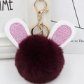 Close-up of fluffy burgundy rabbit fur ball keychain with sparkly pink ears and gold clasp - Gold Key Chain Style / Fuschia