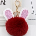 Macro view of plush burgundy faux fur bunny ball keychain with pink glitter ears - Gold Key Chain Style / Burgundy