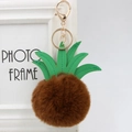 Close-up of brown fur pompom pineapple keychain with green PU leather leaves and gold clasp - 8cm / Brown
