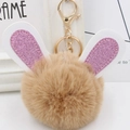 Detailed macro view of bunny ear pompom keychain with brown fur and glittery details - Gold Key Chain Style / Khaki