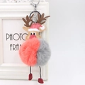 Close-up of reindeer plush pompom keychain with red leather boots on a white frame - Orange And Gray