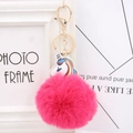 Close-up of fluffy pink pom-pom with rainbow unicorn charm and golden lobster clasp - Rose Red