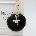 Close-up of fluffy black faux fur ball keychain featuring a golden ballerina charm with pearls - 8cm Faux Fur / Black